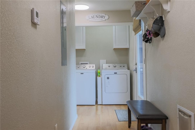 washroom with light hardwood / wood-style flooring, washer and dryer, and cabinets