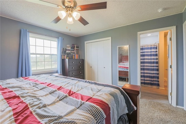 bedroom with a closet, ceiling fan, carpet floors, and a textured ceiling