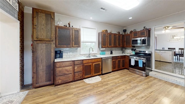 kitchen with light hardwood / wood-style floors, decorative backsplash, stainless steel appliances, and sink