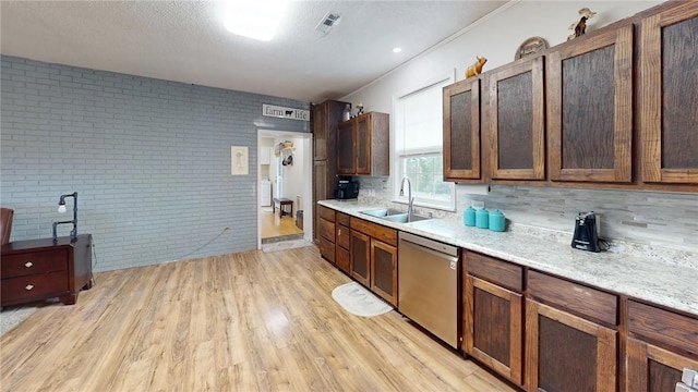 kitchen with light wood-type flooring, brick wall, sink, dishwasher, and a textured ceiling