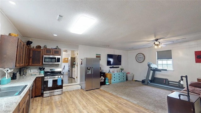 kitchen featuring light hardwood / wood-style flooring, stainless steel appliances, a textured ceiling, decorative backsplash, and sink