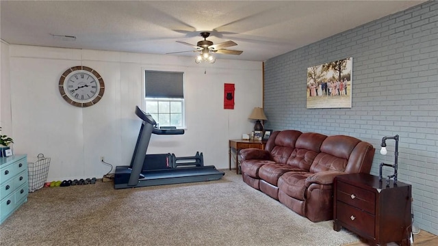 living room with ceiling fan, brick wall, and light colored carpet