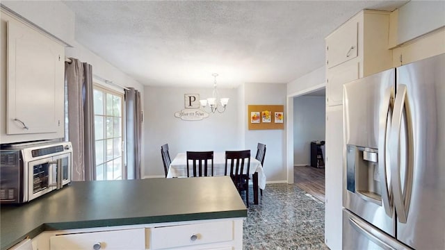 kitchen featuring a notable chandelier, a textured ceiling, white cabinets, decorative light fixtures, and stainless steel fridge