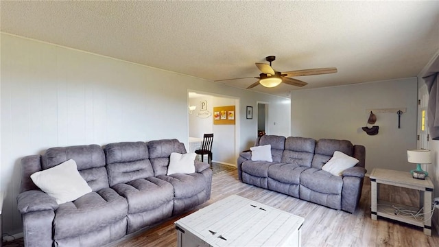 living room featuring ceiling fan, light hardwood / wood-style flooring, and a textured ceiling