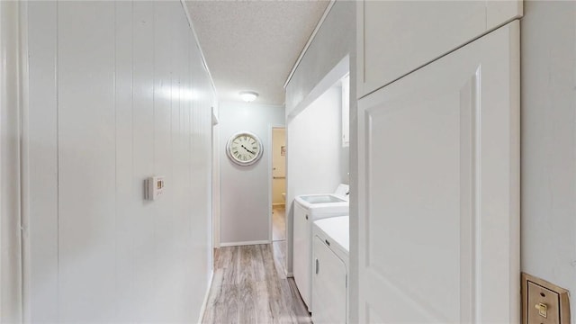 laundry area featuring washer and dryer, a textured ceiling, and light hardwood / wood-style floors