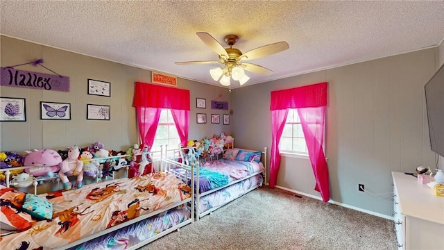 bedroom featuring ceiling fan, carpet flooring, multiple windows, and a textured ceiling