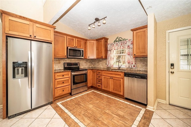 kitchen with appliances with stainless steel finishes, backsplash, a sink, and light tile patterned flooring