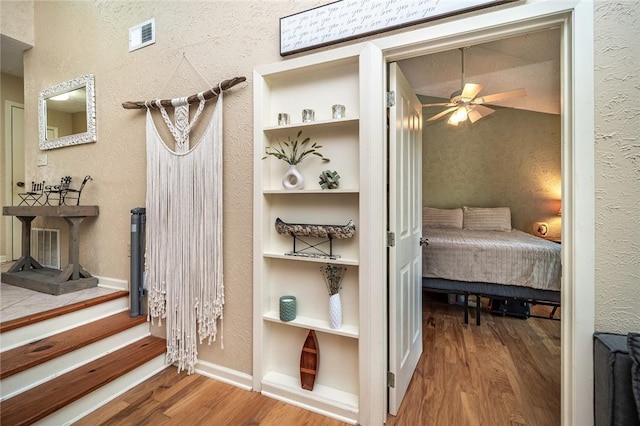 interior space with a textured wall, wood finished floors, and visible vents