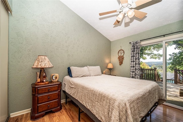 bedroom with a textured wall, wood finished floors, a ceiling fan, access to exterior, and vaulted ceiling