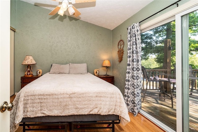 bedroom with access to exterior, a textured wall, a ceiling fan, a textured ceiling, and wood finished floors