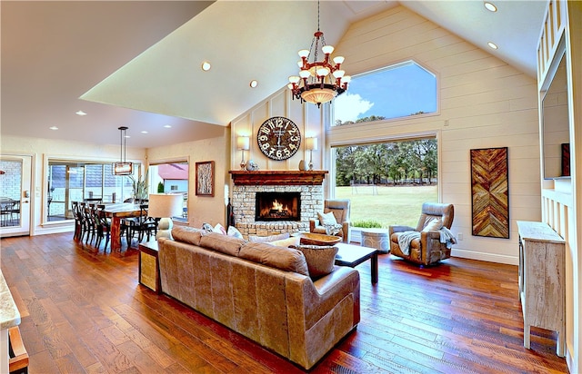 living room with high vaulted ceiling, a wealth of natural light, dark hardwood / wood-style flooring, and a stone fireplace