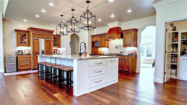 kitchen with hanging light fixtures, white cabinetry, a breakfast bar, a center island with sink, and dark hardwood / wood-style floors