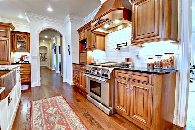 kitchen with dark stone countertops, stainless steel range, dark hardwood / wood-style floors, and custom range hood