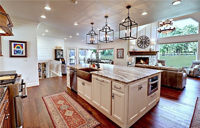 kitchen featuring pendant lighting, white cabinets, a kitchen island with sink, and sink