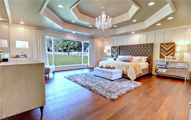 bedroom with crown molding, a tray ceiling, a chandelier, and hardwood / wood-style flooring