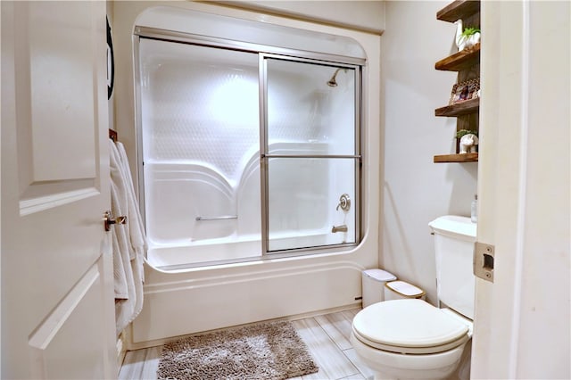 bathroom featuring bath / shower combo with glass door, hardwood / wood-style flooring, and toilet