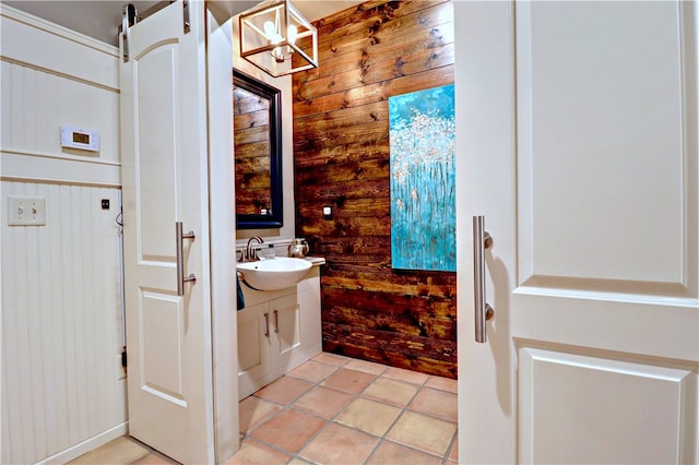 bathroom with a notable chandelier, wood walls, tile patterned flooring, and vanity