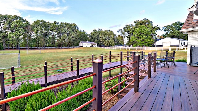 wooden terrace with a yard, an outdoor structure, and a rural view