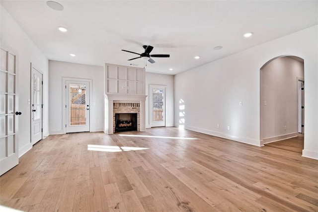 unfurnished living room with ceiling fan, a fireplace, and light hardwood / wood-style floors