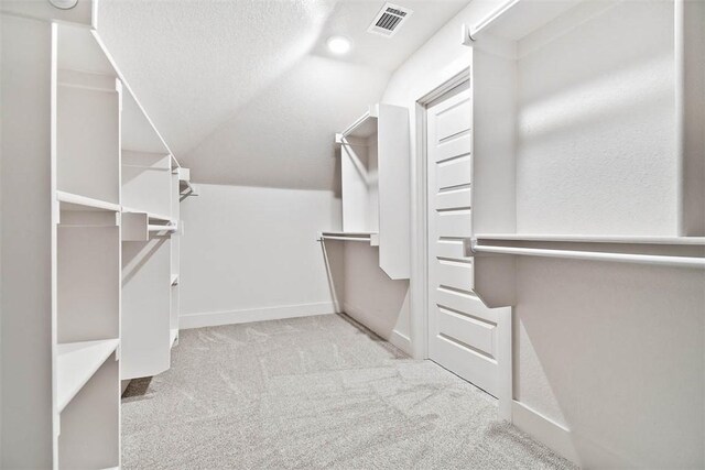 walk in closet with lofted ceiling and light colored carpet