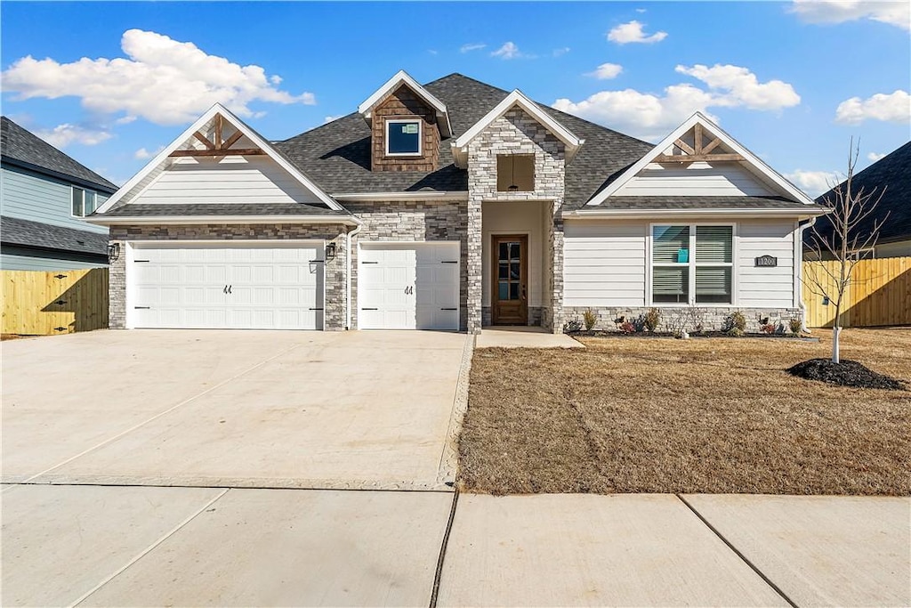 view of front facade featuring an attached garage, stone siding, fence, and concrete driveway