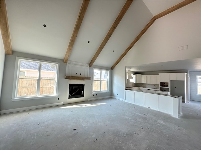 unfurnished living room featuring a fireplace, high vaulted ceiling, plenty of natural light, and beamed ceiling