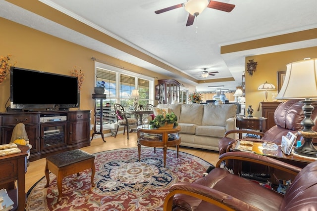 living room with crown molding, ceiling fan, and light hardwood / wood-style flooring