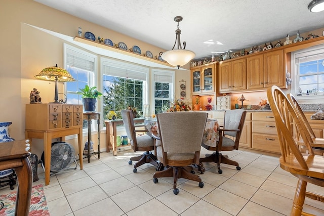 dining space with a textured ceiling, plenty of natural light, and light tile patterned flooring