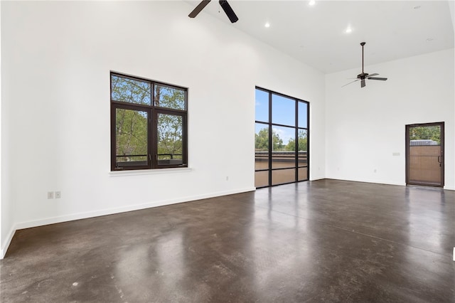 empty room with finished concrete floors, a towering ceiling, and a ceiling fan