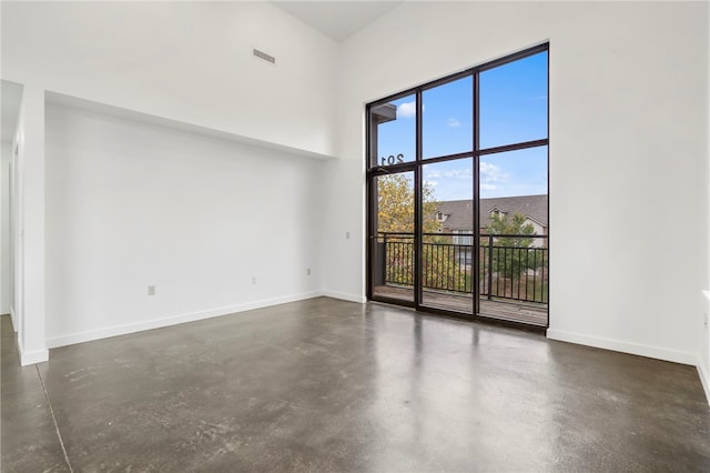 unfurnished room featuring a towering ceiling, baseboards, visible vents, and concrete flooring