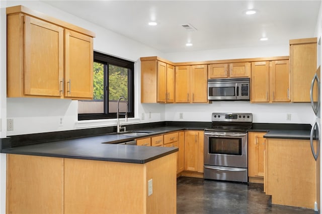 kitchen featuring a peninsula, dark countertops, appliances with stainless steel finishes, and a sink