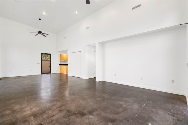 unfurnished living room with visible vents, a high ceiling, ceiling fan, concrete floors, and baseboards