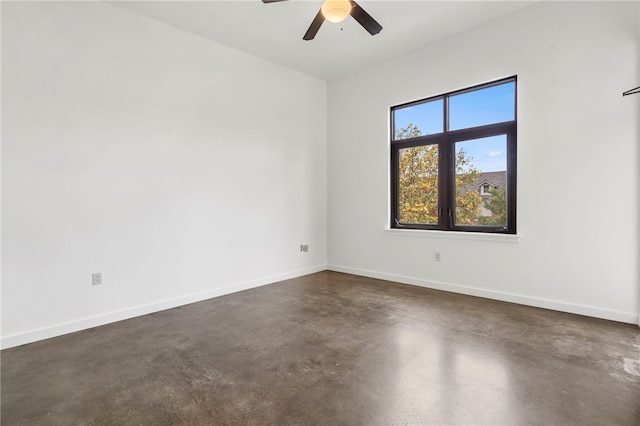 empty room with finished concrete floors, ceiling fan, and baseboards