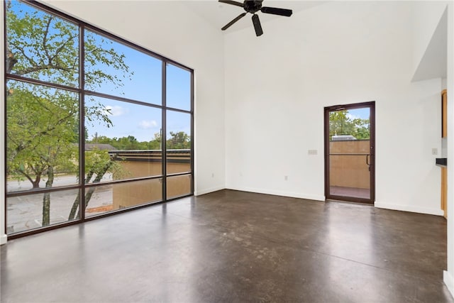 spare room featuring concrete flooring, a high ceiling, plenty of natural light, and baseboards