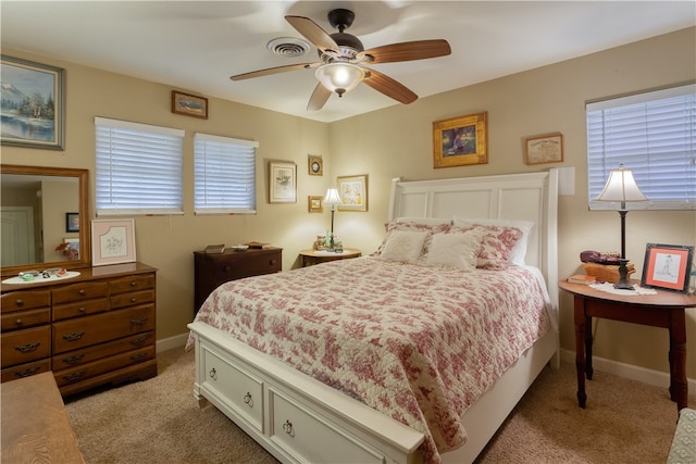 bedroom with multiple windows, ceiling fan, and light colored carpet