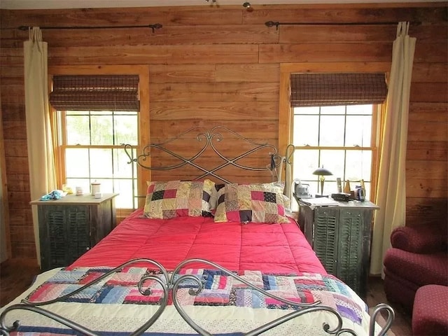 bedroom with multiple windows and wood walls