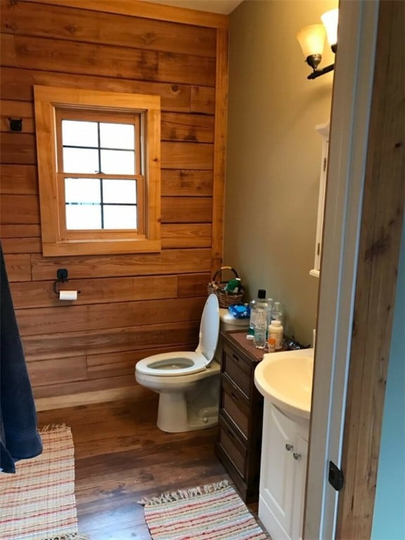 bathroom featuring wood walls, vanity, hardwood / wood-style floors, and toilet