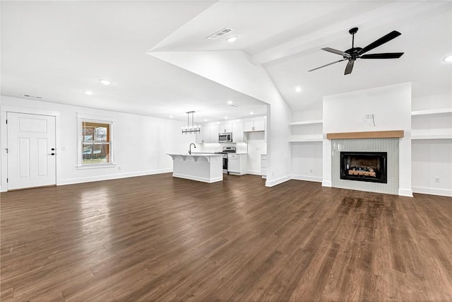 unfurnished living room featuring visible vents, baseboards, dark wood-style floors, and vaulted ceiling with beams