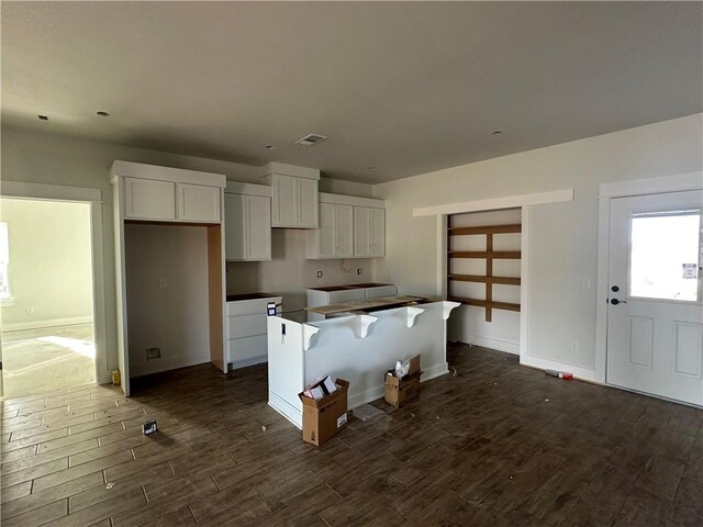 kitchen featuring white cabinetry, a kitchen island, and dark wood-type flooring