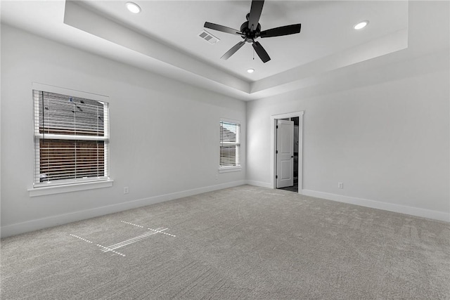 carpeted empty room with recessed lighting, a raised ceiling, visible vents, and baseboards