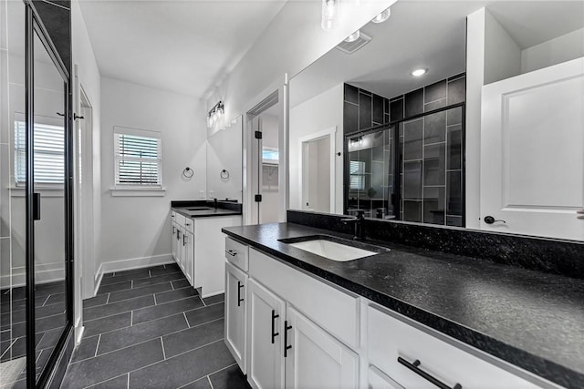 bathroom with two vanities, a sink, a shower stall, and baseboards