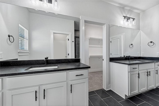 full bathroom with two vanities, a sink, a walk in closet, and tile patterned floors