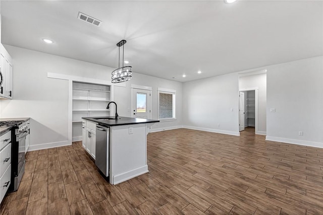 kitchen featuring a sink, visible vents, range with gas stovetop, dishwasher, and dark countertops