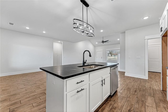 kitchen with a sink, wood tiled floor, dishwasher, an island with sink, and dark countertops