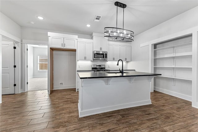 kitchen with visible vents, dark countertops, appliances with stainless steel finishes, dark wood-style flooring, and a sink