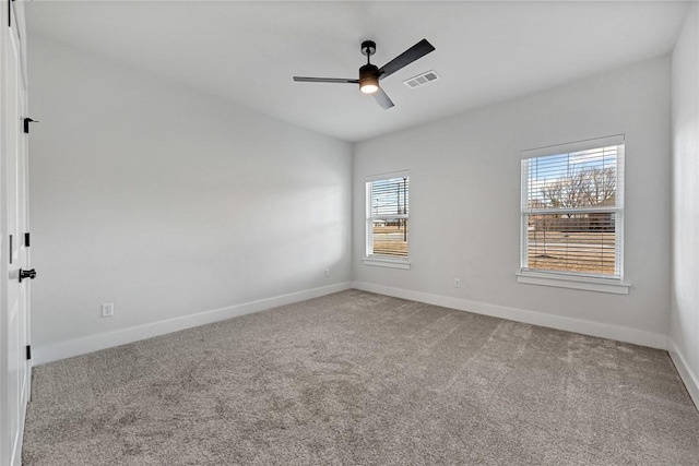 carpeted spare room featuring a ceiling fan, visible vents, and baseboards