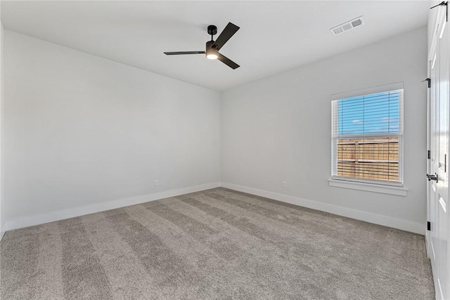 spare room featuring carpet floors, a ceiling fan, visible vents, and baseboards