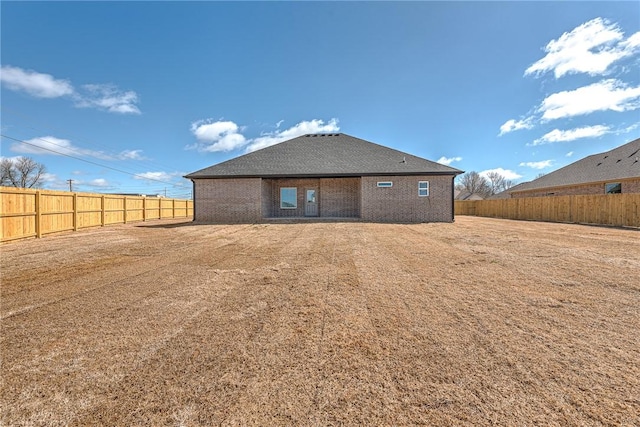 rear view of house featuring a fenced backyard and brick siding