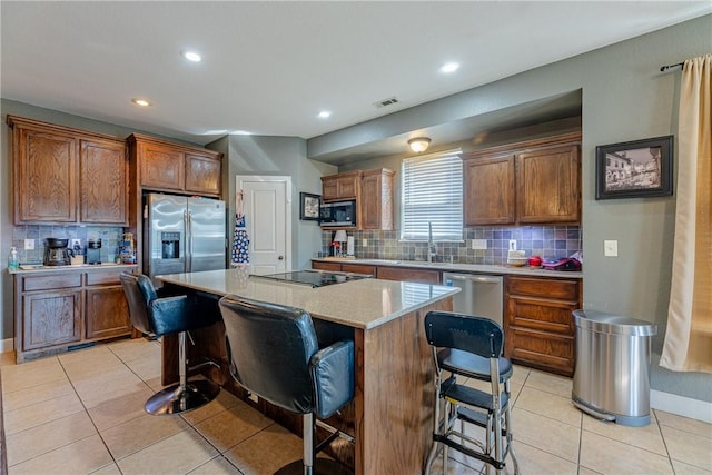 kitchen with light tile patterned floors, appliances with stainless steel finishes, a breakfast bar, and a center island