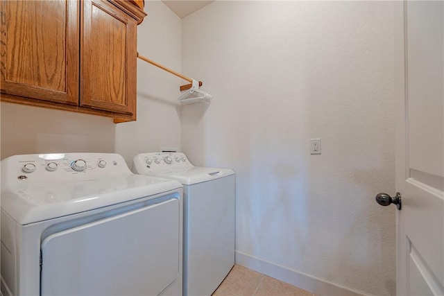 laundry room featuring cabinets, light tile patterned flooring, and washing machine and clothes dryer